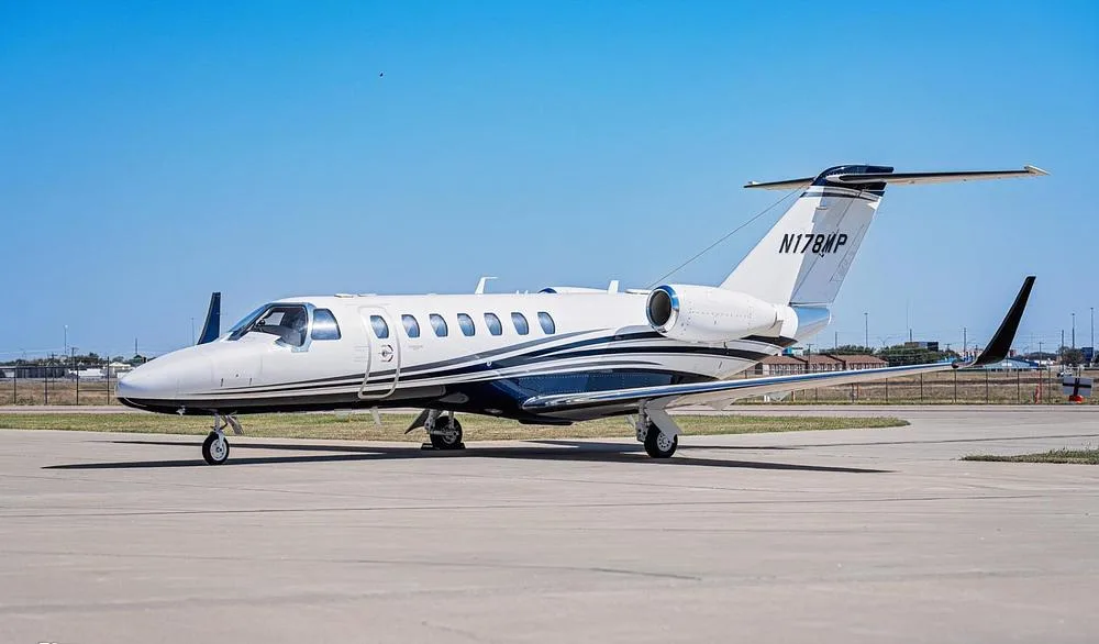 A white and blue Cessna Citation M2 jet, registration N178MP, parked on an airport tarmac under a clear blue sky.