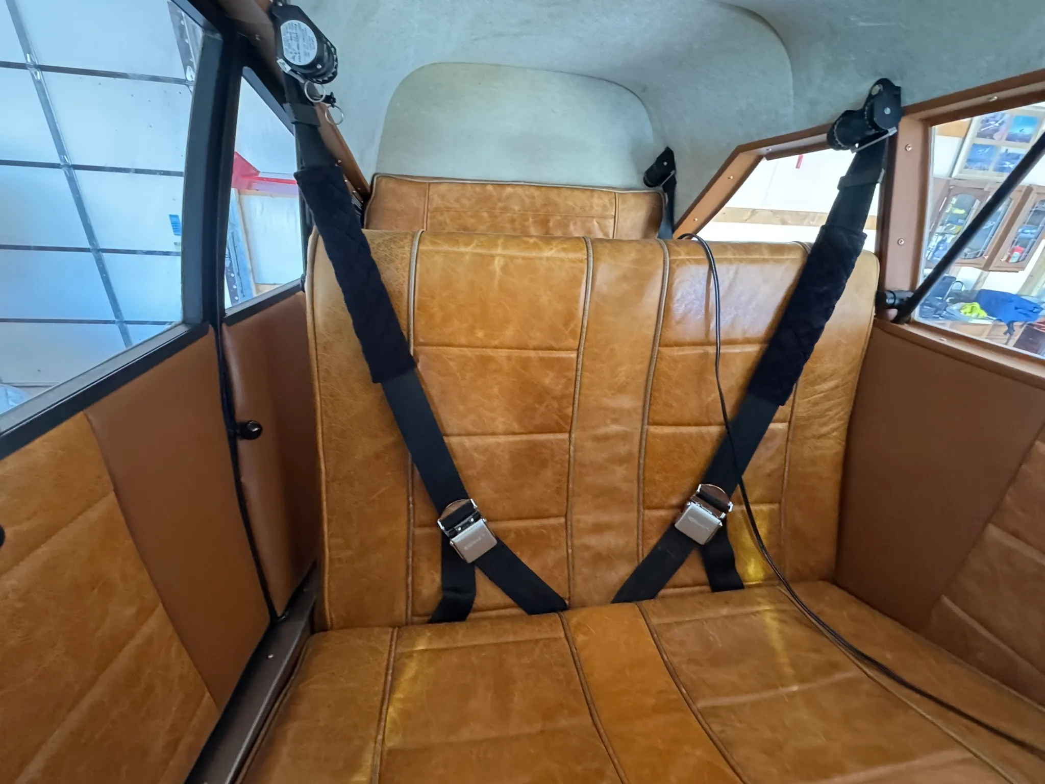 The aircraft's tan leather rear seats with black seatbelts.