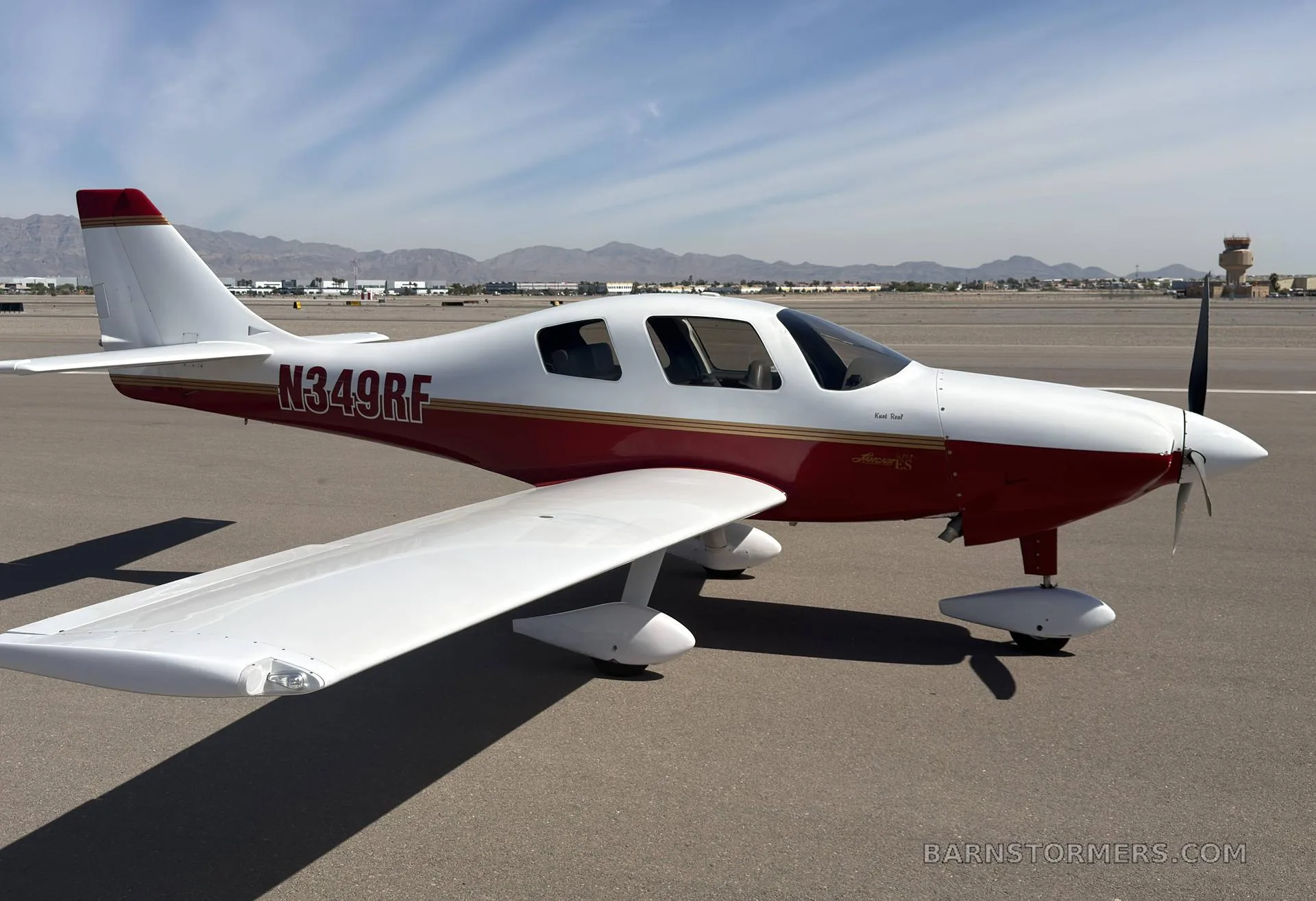 A white and red single-engine aircraft, N349RF, viewed from the side on an airfield.