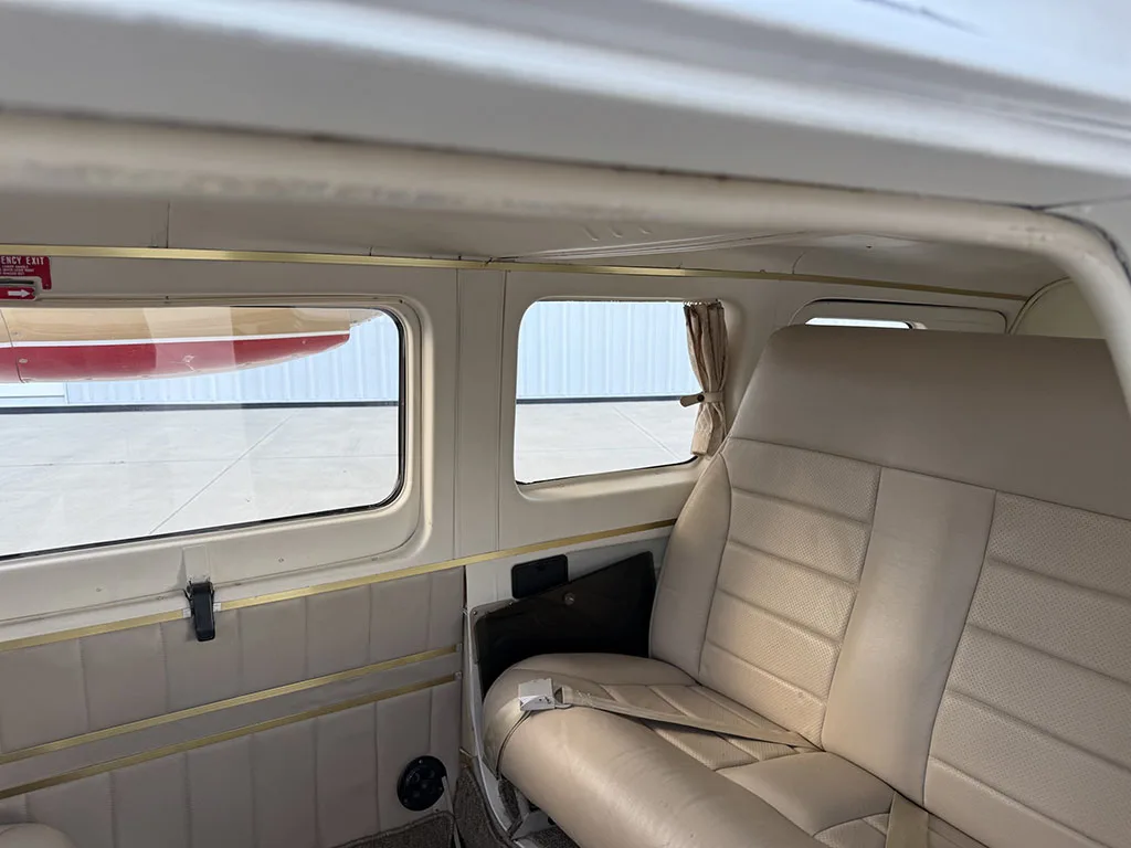 The beige leather passenger seats and windows of the aircraft cabin are visible.