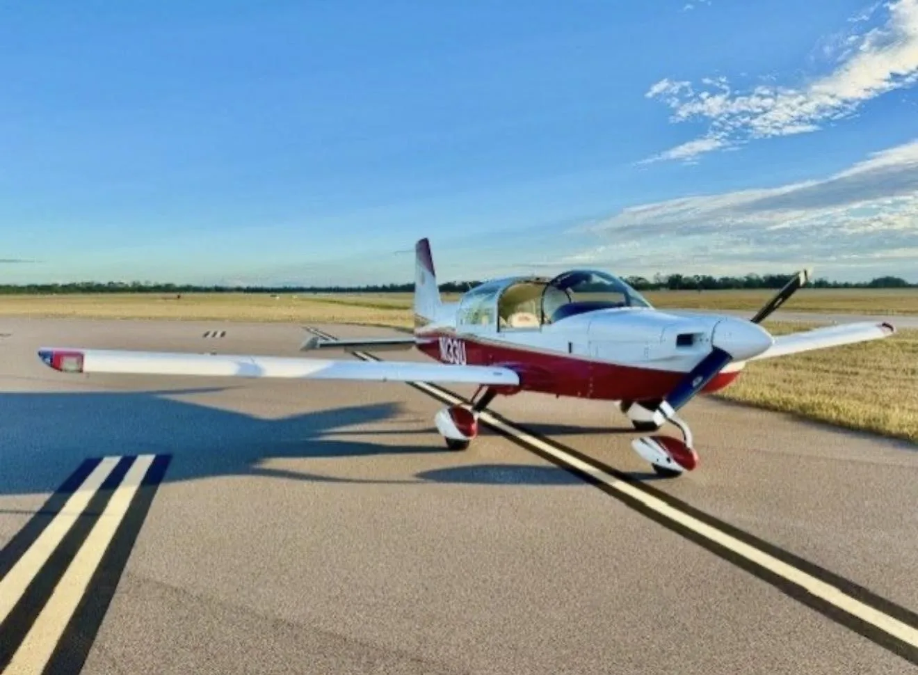 A side view of a white and red American General AG-5B Tiger aircraft with registration N133U on an airfield.