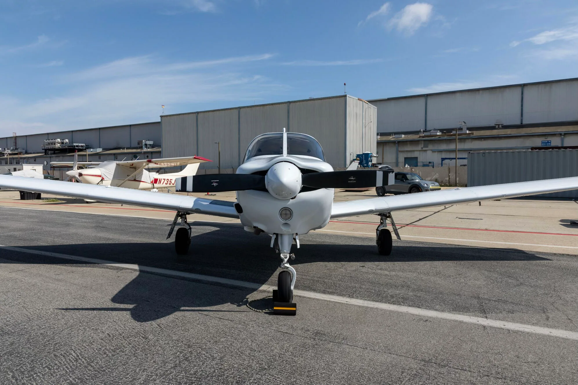 A head-on view of a white Piper PA-28-181 Archer III aircraft parked on an airfield.