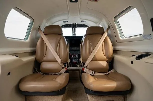 The tan leather pilot and co-pilot seats in the cockpit of a small aircraft, viewed from the cabin.