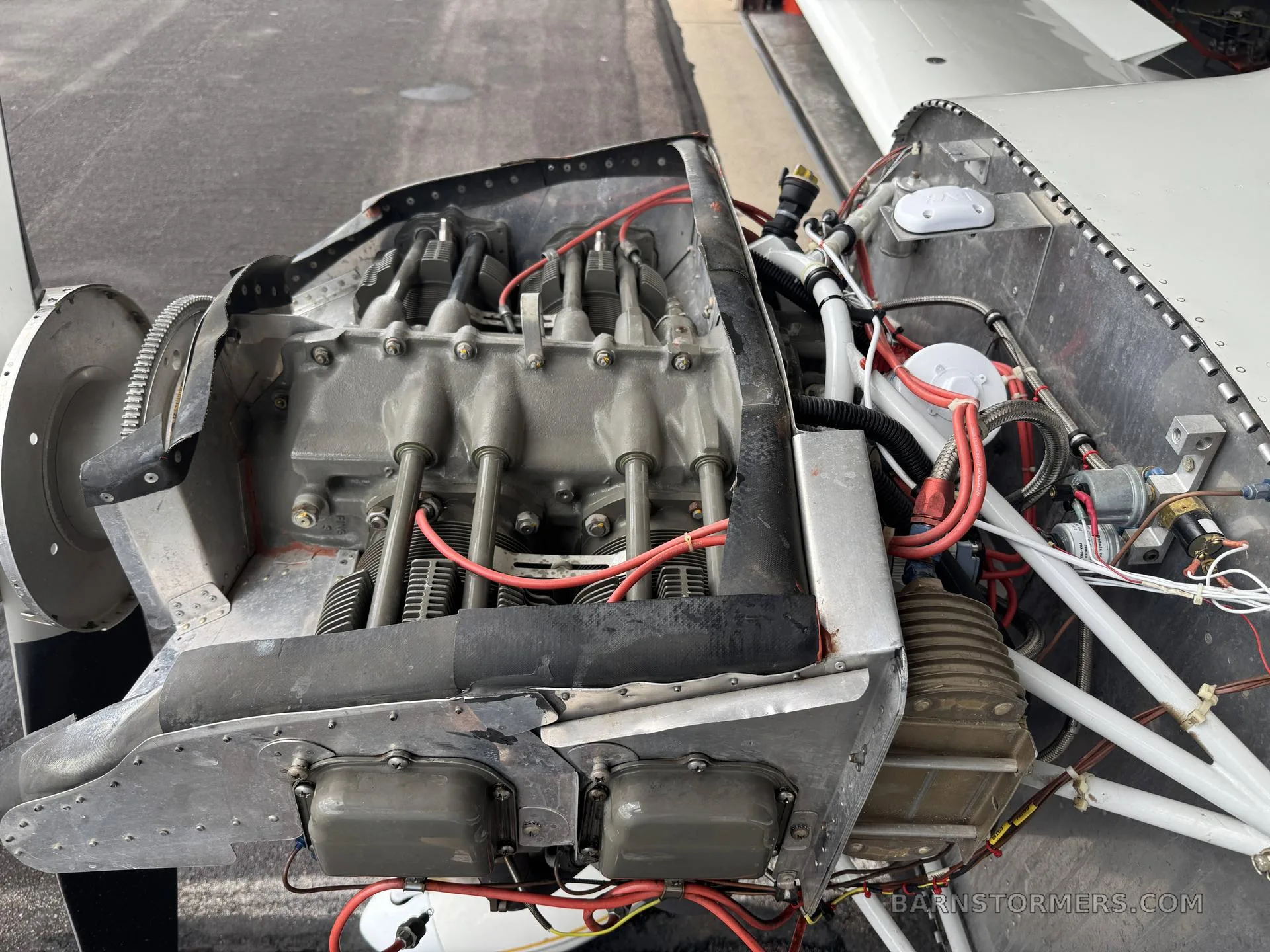 A close-up view of an exposed aircraft engine with its cowling removed, showing cylinders, wires, and components.