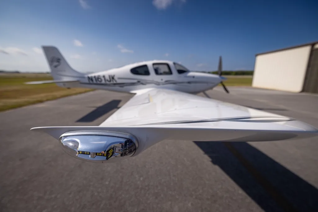 A low-angle view of the right wingtip of a white Cirrus SR22 Turbo aircraft, registration N161JK, on an airfield.