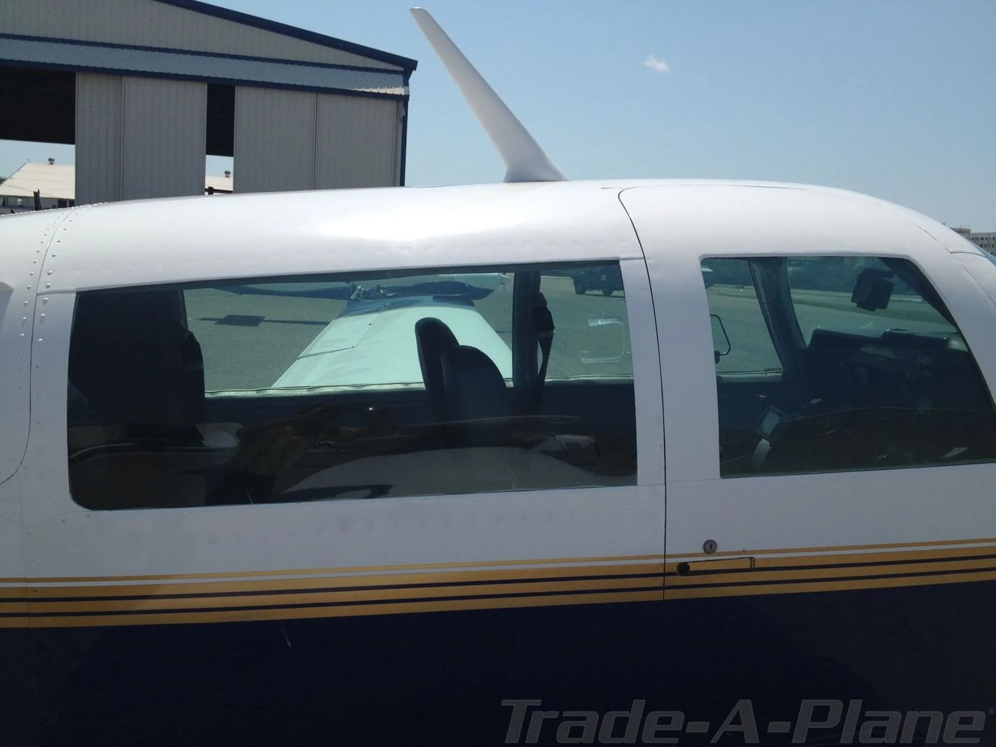 Close-up of the side of the aircraft showing the blue fuselage, white top, and gold stripe with tinted windows.