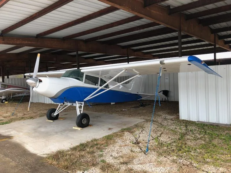 A blue and white Maule aircraft, N336X, with its propeller visible, parked in a hangar.
