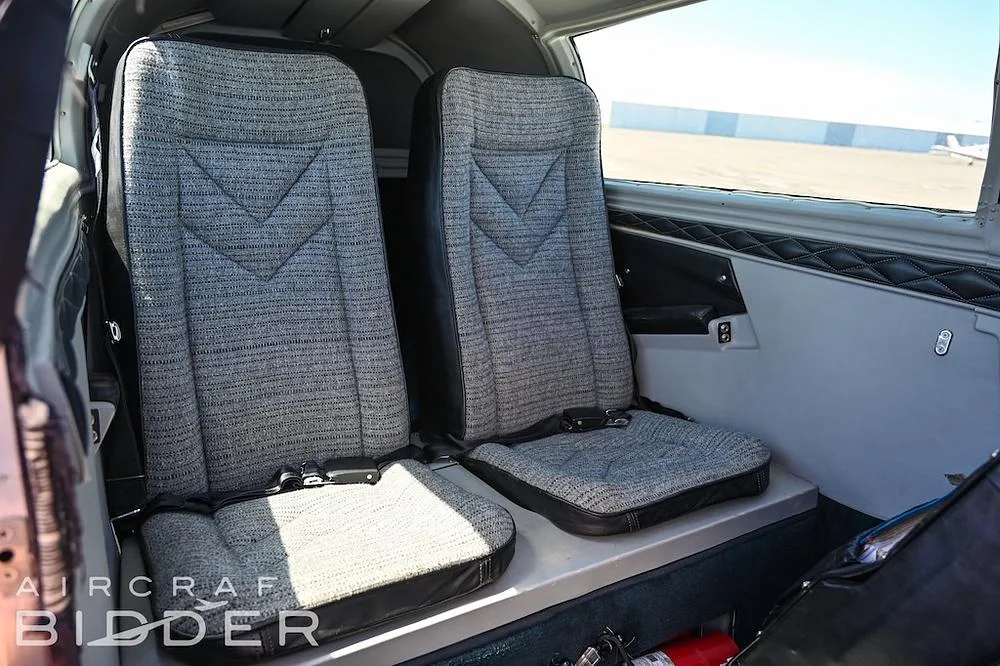 Two grey fabric passenger seats with black trim are visible in the aircraft's cabin.