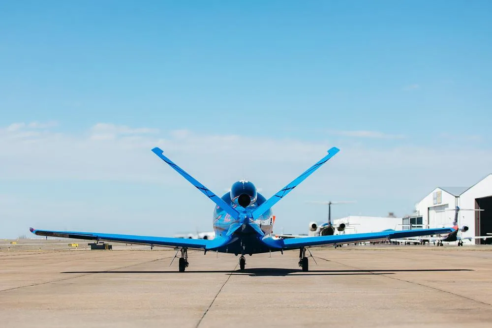 A rear view of the blue and black Cirrus Vision Jet (N3EE) parked on an airfield.