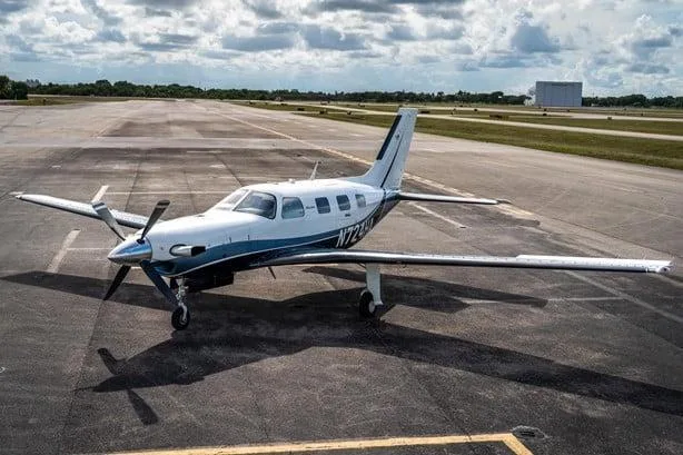 An aerial view of the white and blue Piper M500 (Meridian) aircraft, registration N724HA, parked on an airfield.