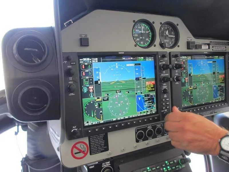 A close-up view of a helicopter's glass cockpit displays, showing navigation and flight information.