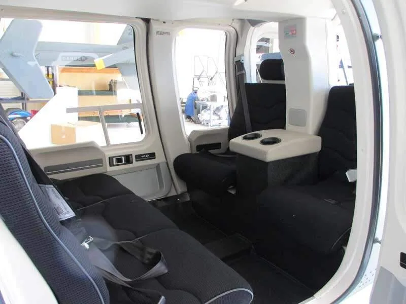 The interior cabin of a helicopter with black seats and a light-colored center console.