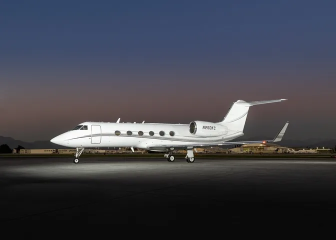 A white Gulfstream business jet, registration N250KC, is parked on an airfield at dusk.