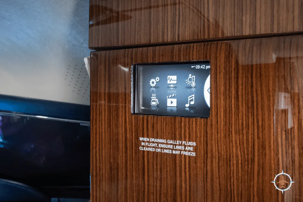 A close-up of an interior control panel embedded in dark wood paneling, showing various icons and text.