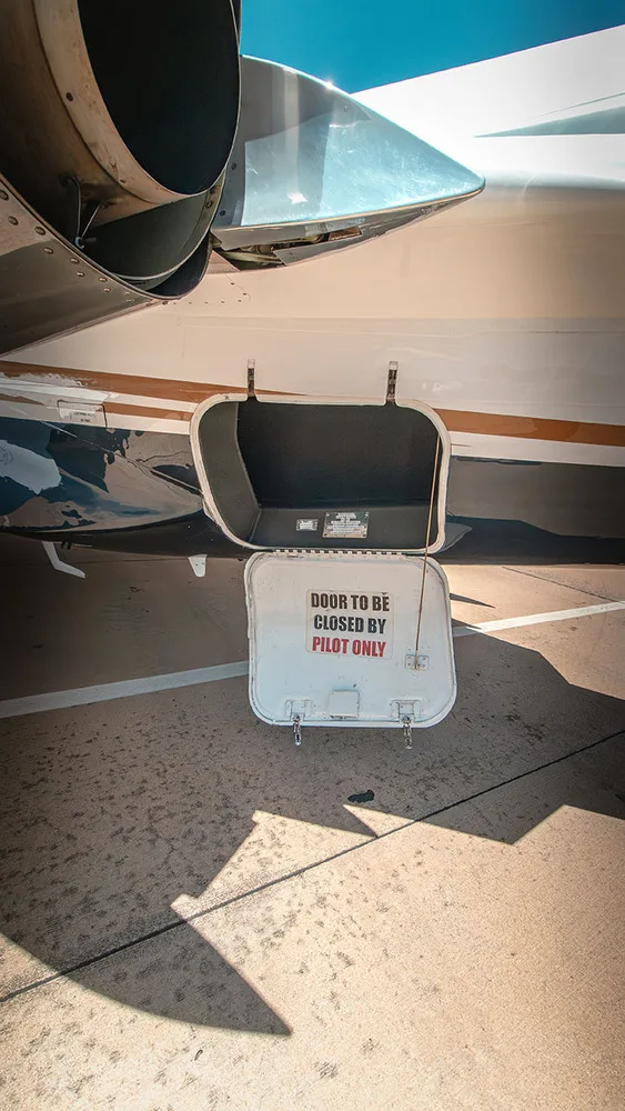 A close-up of an open service door on the underside of a white Cessna Citation jet, with a warning "DOOR TO BE CLOSED BY PILOT ONLY".