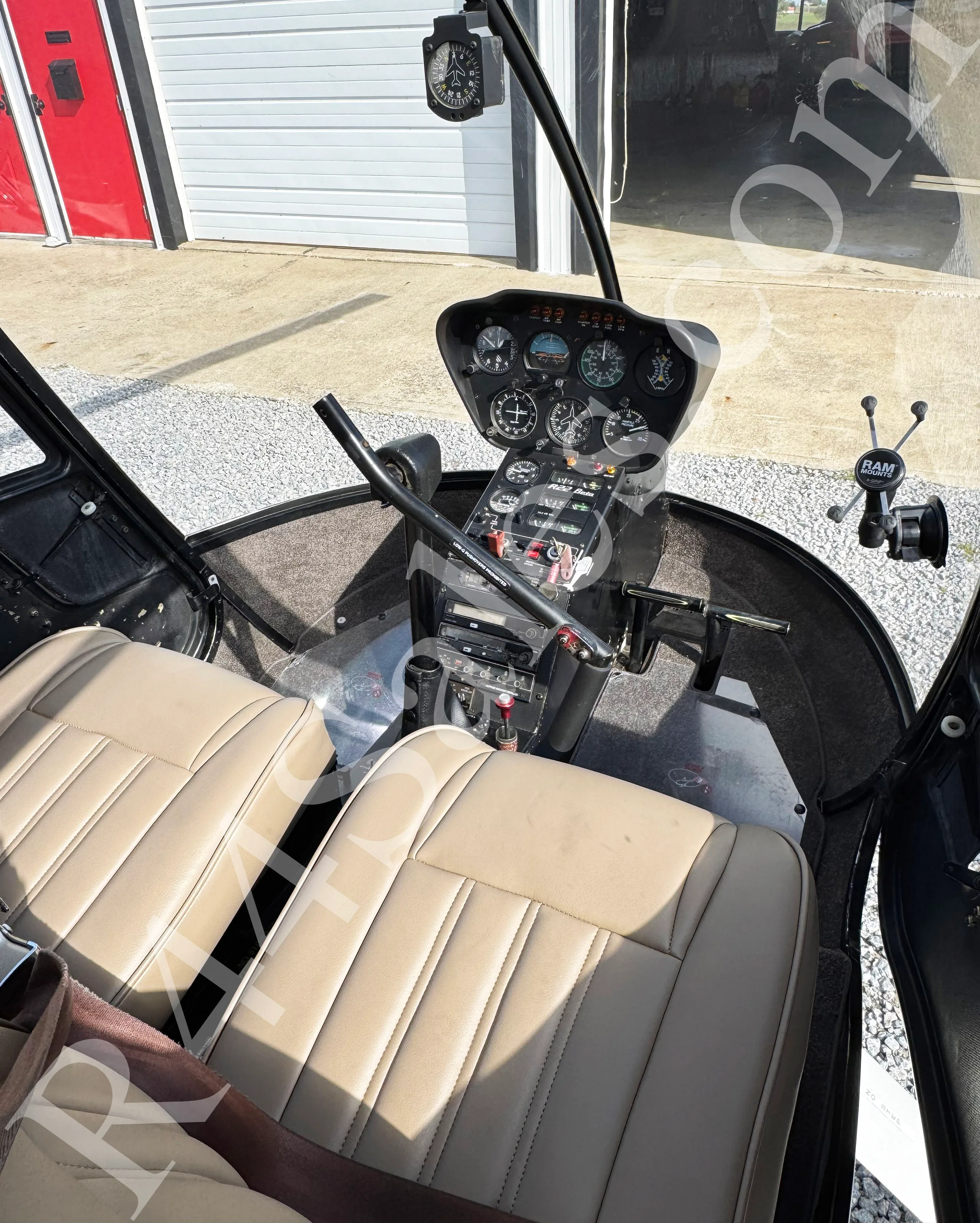An overhead view of the Robinson R22 helicopter cockpit with its instrument panel and tan seats.