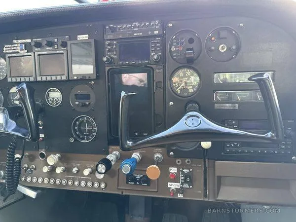 The cockpit instrument panel of a small aircraft, showing various gauges, avionics, and a control yoke.