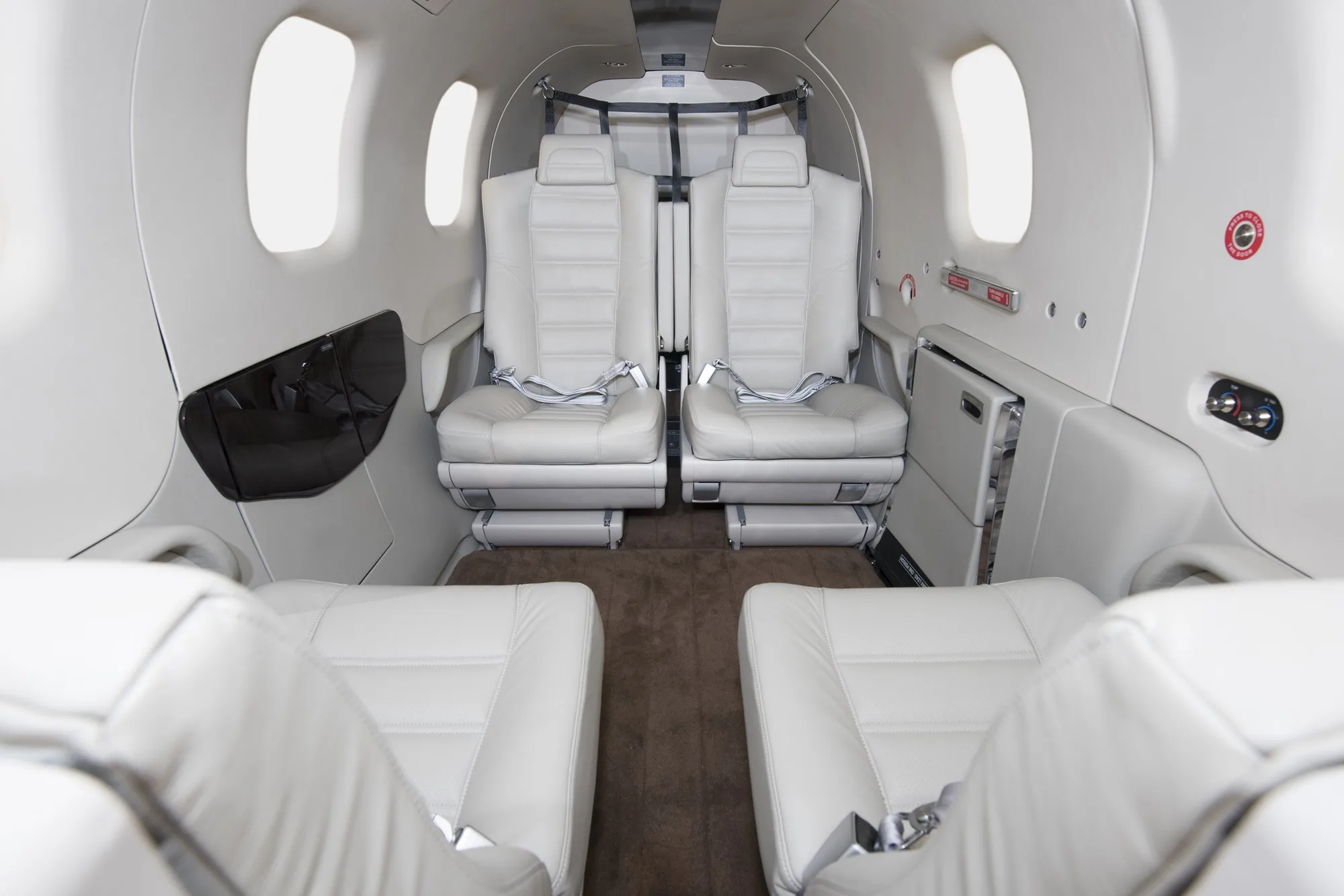 Interior view of an aircraft cabin with white leather seats.