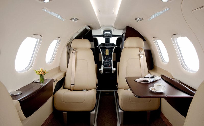 Interior view of an aircraft cabin with leather seats and a small table.
