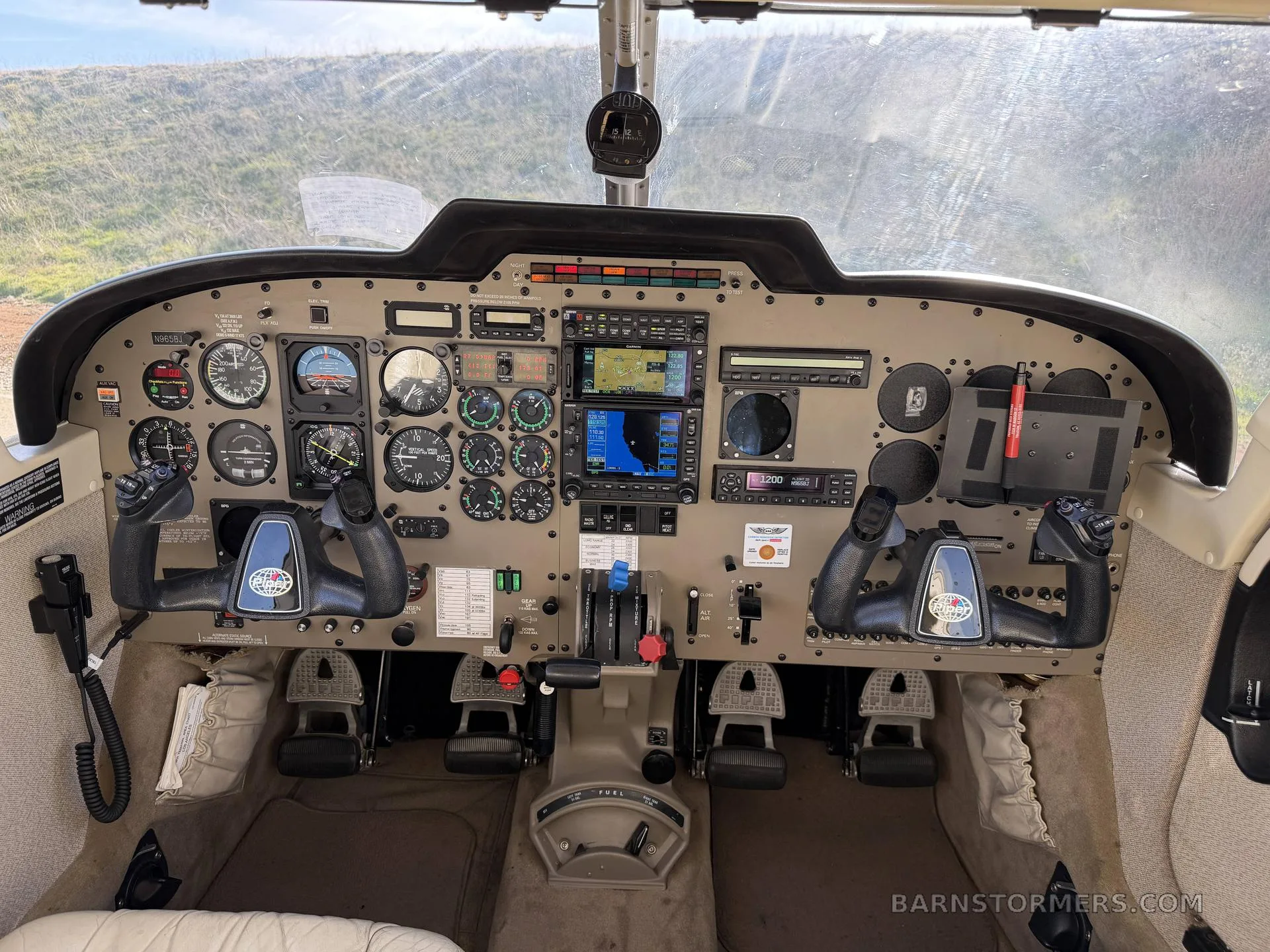 The cockpit of a Piper Saratoga II TC, showing the instrument panel with analog gauges and modern digital displays, dual yokes, and center console.