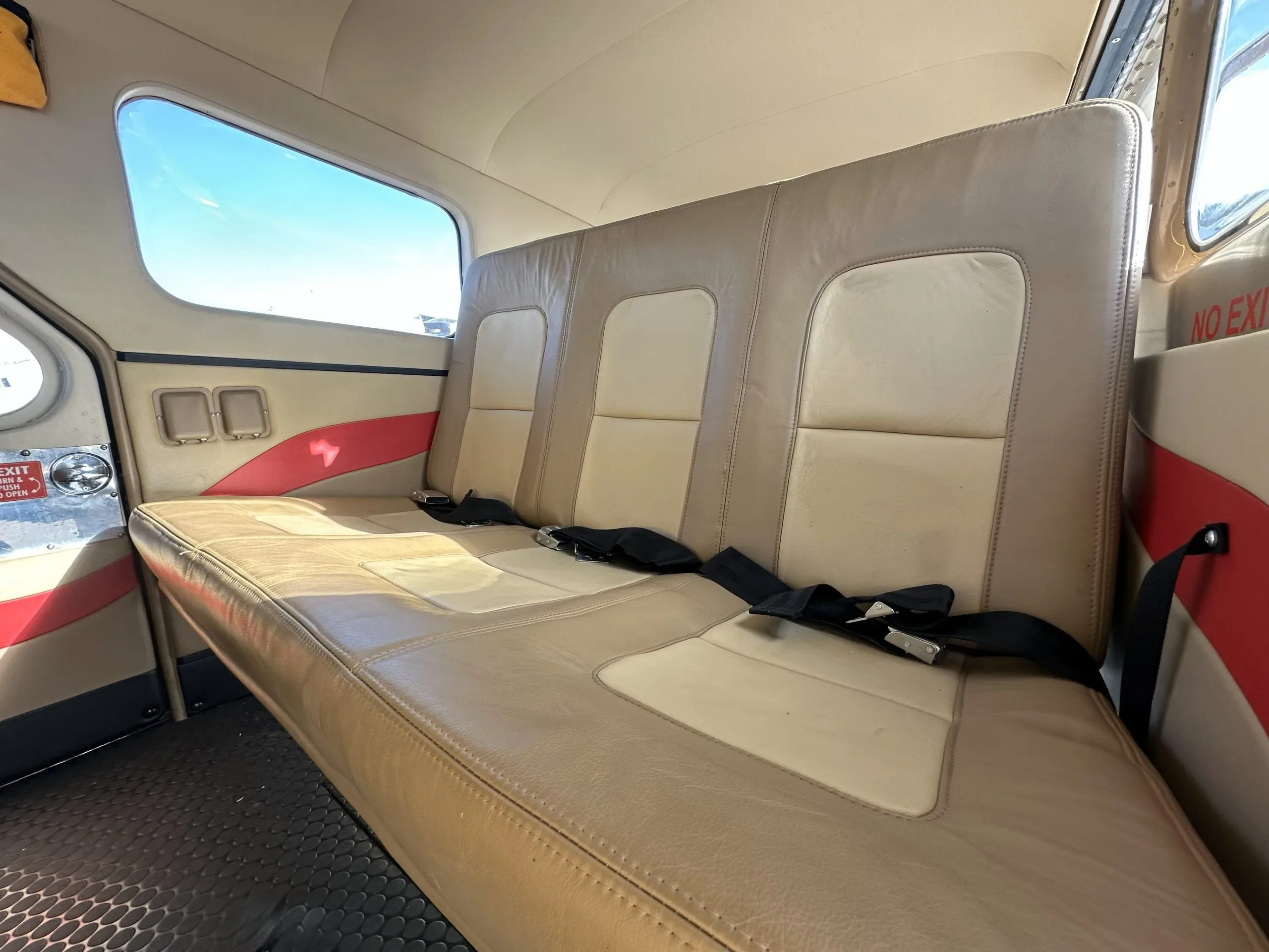 View of the tan leather rear bench seat inside the aircraft cabin.