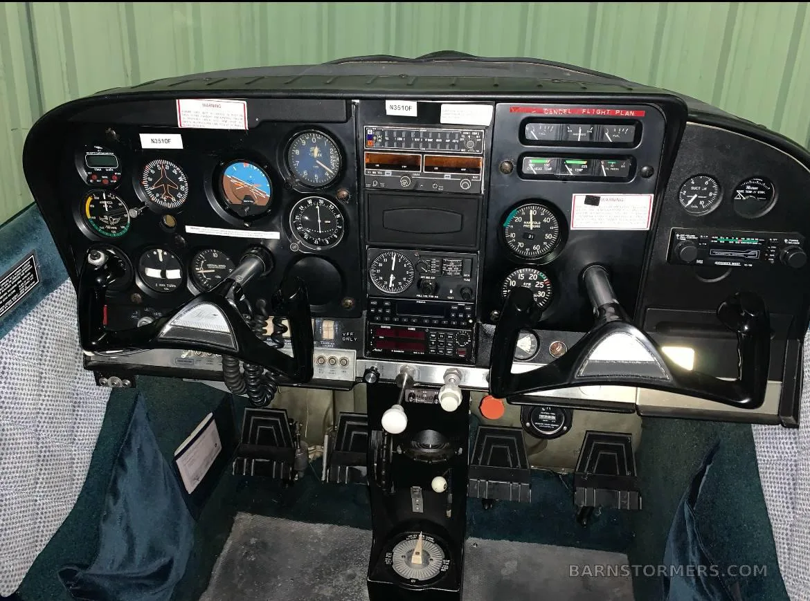 The cockpit of a Cessna 172, showing the instrument panel with analog gauges and avionics, and dual yokes.