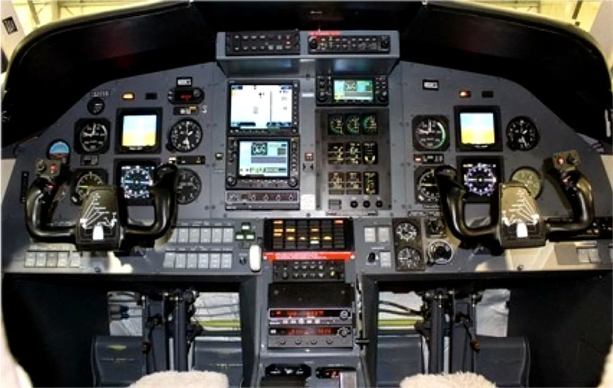 The cockpit of an aircraft showing the instrument panel with multiple screens and controls.
