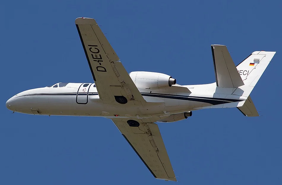 A Cessna Citation Mustang aircraft, registration D-IECI, in flight against a clear blue sky.