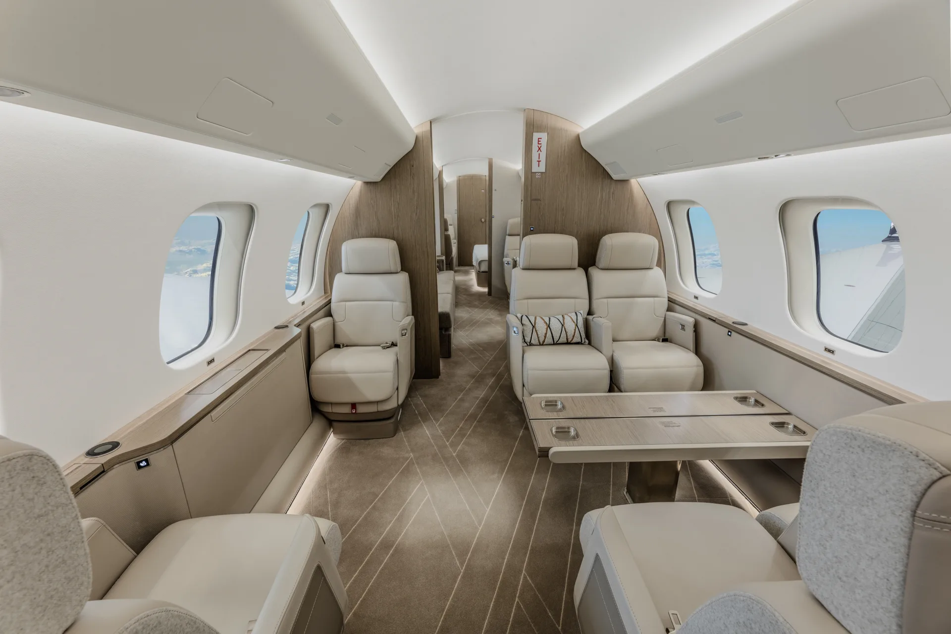A private jet cabin featuring a wooden table with cup holders and cream leather seating.