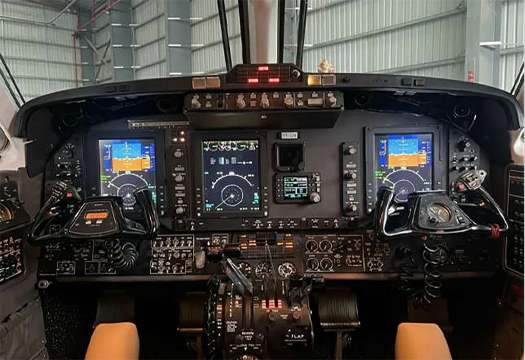 The cockpit of a modern turboprop aircraft, featuring multiple digital displays and control yokes.