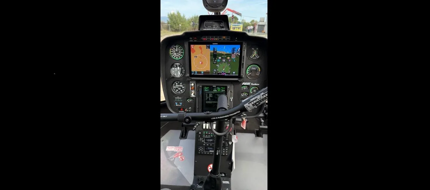 The instrument panel of a Robinson R66 helicopter, showing multiple screens and gauges.
