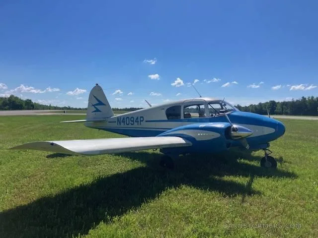 A blue and white Piper Pacer (N4094P) is parked on a grassy airfield under a clear sky.