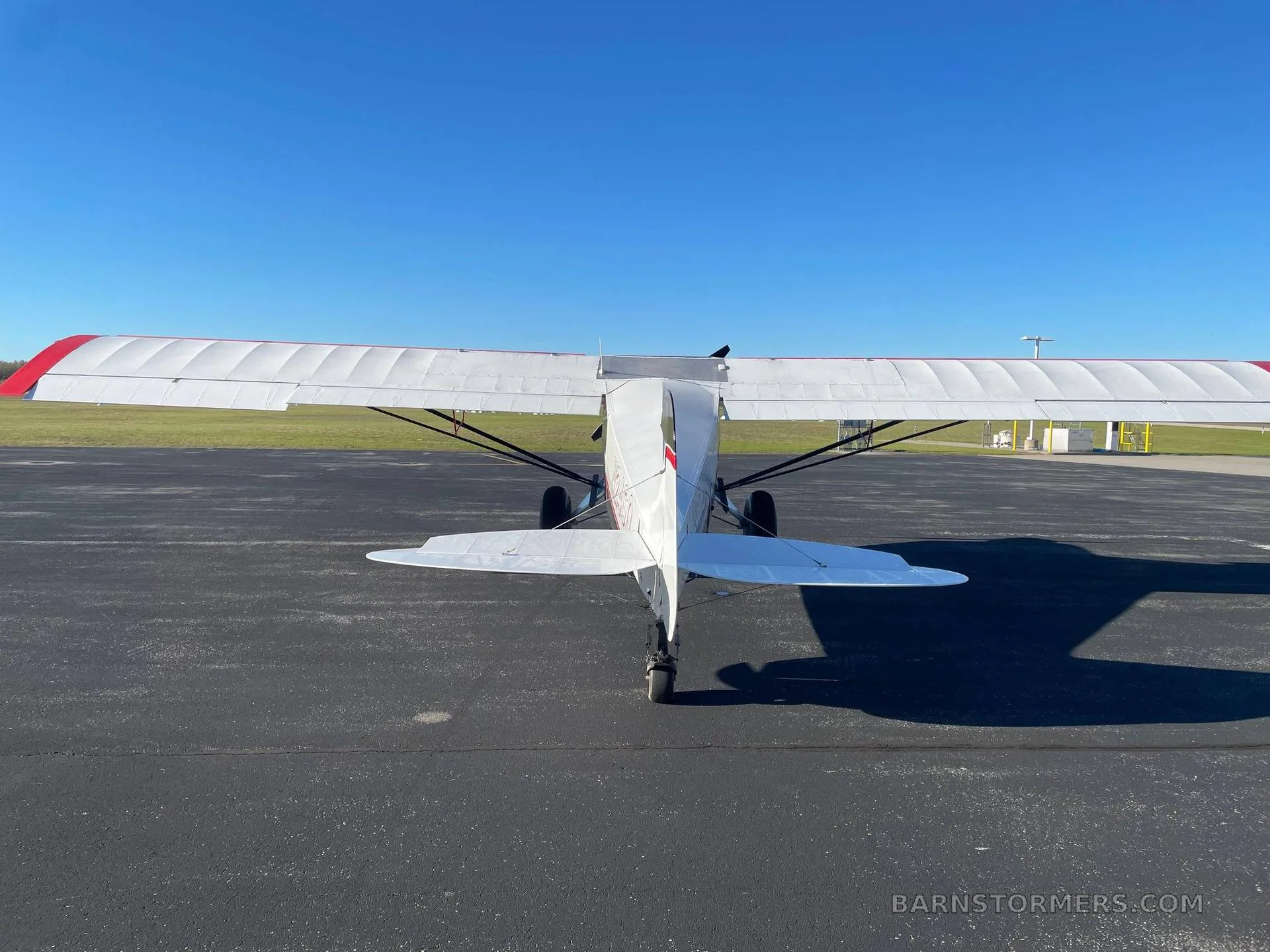 A direct rear view of a white and red high-wing aircraft with registration N24SQ, parked on an asphalt apron.