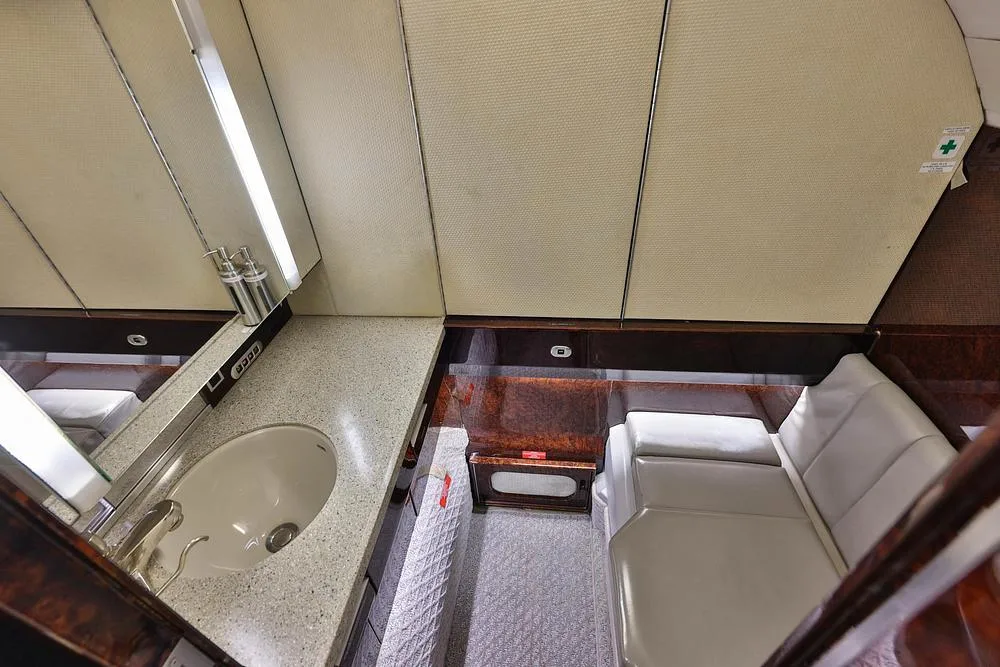 An overhead view of the aircraft's lavatory or galley area with a sink and a light-colored bench.