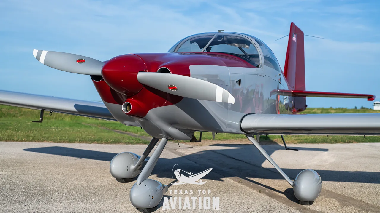 A close-up front view of the gray and red single-engine aircraft, N1359L, showing its propeller and landing gear.