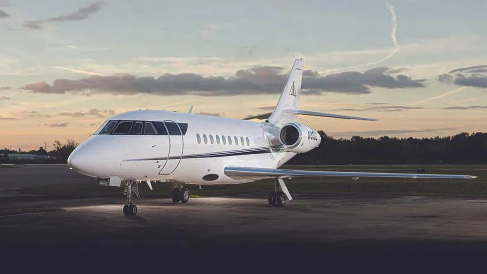 A front-quarter view of the white business jet N88GD with a dark blue stripe, parked on an tarmac at dusk.