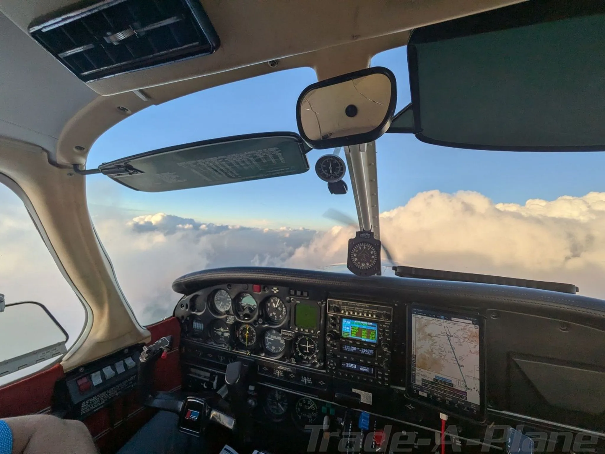 A view from the cockpit of an aircraft showing the instrument panel and clouds outside.