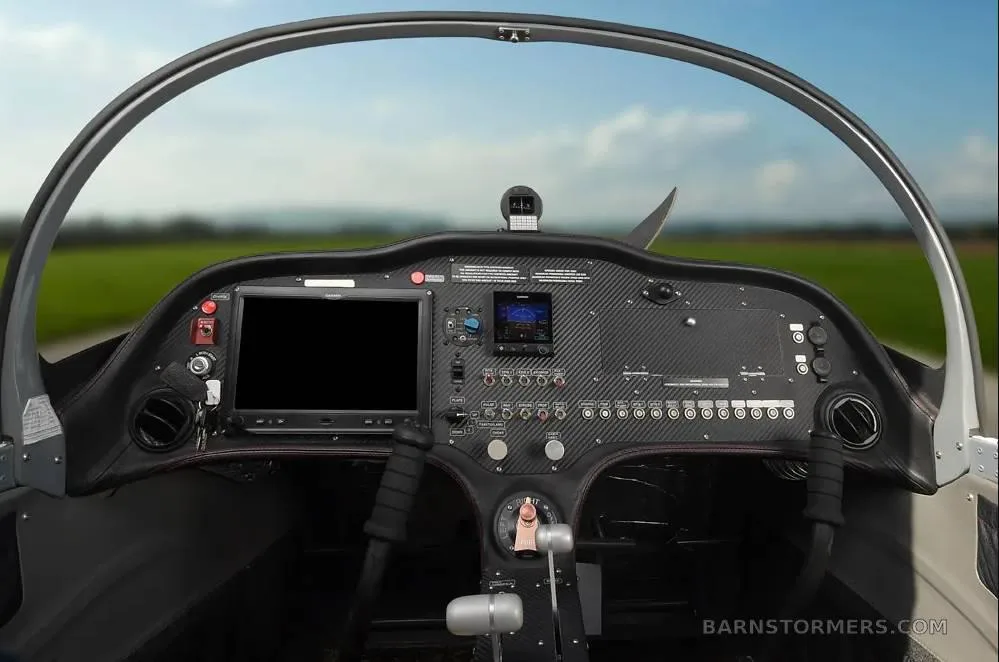 A clean cockpit view of a Sling aircraft, showing the instrument panel with a large display and controls, with a runway visible through the canopy.