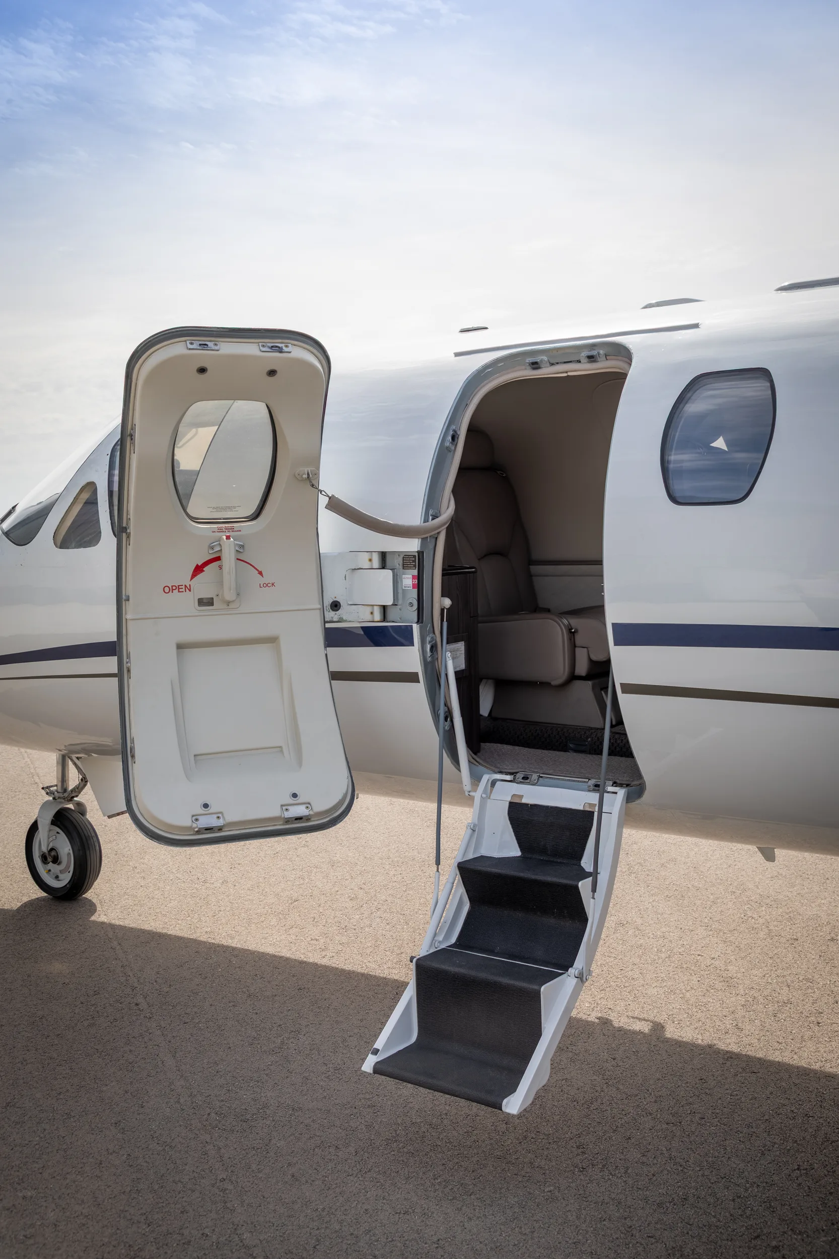 The open main cabin door and integrated airstairs of a white Cessna Citation Excel on the tarmac.