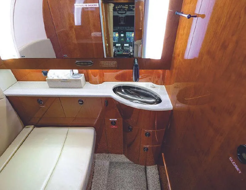 A view of the aircraft's lavatory or galley area with a sink, mirror, and wood cabinetry.