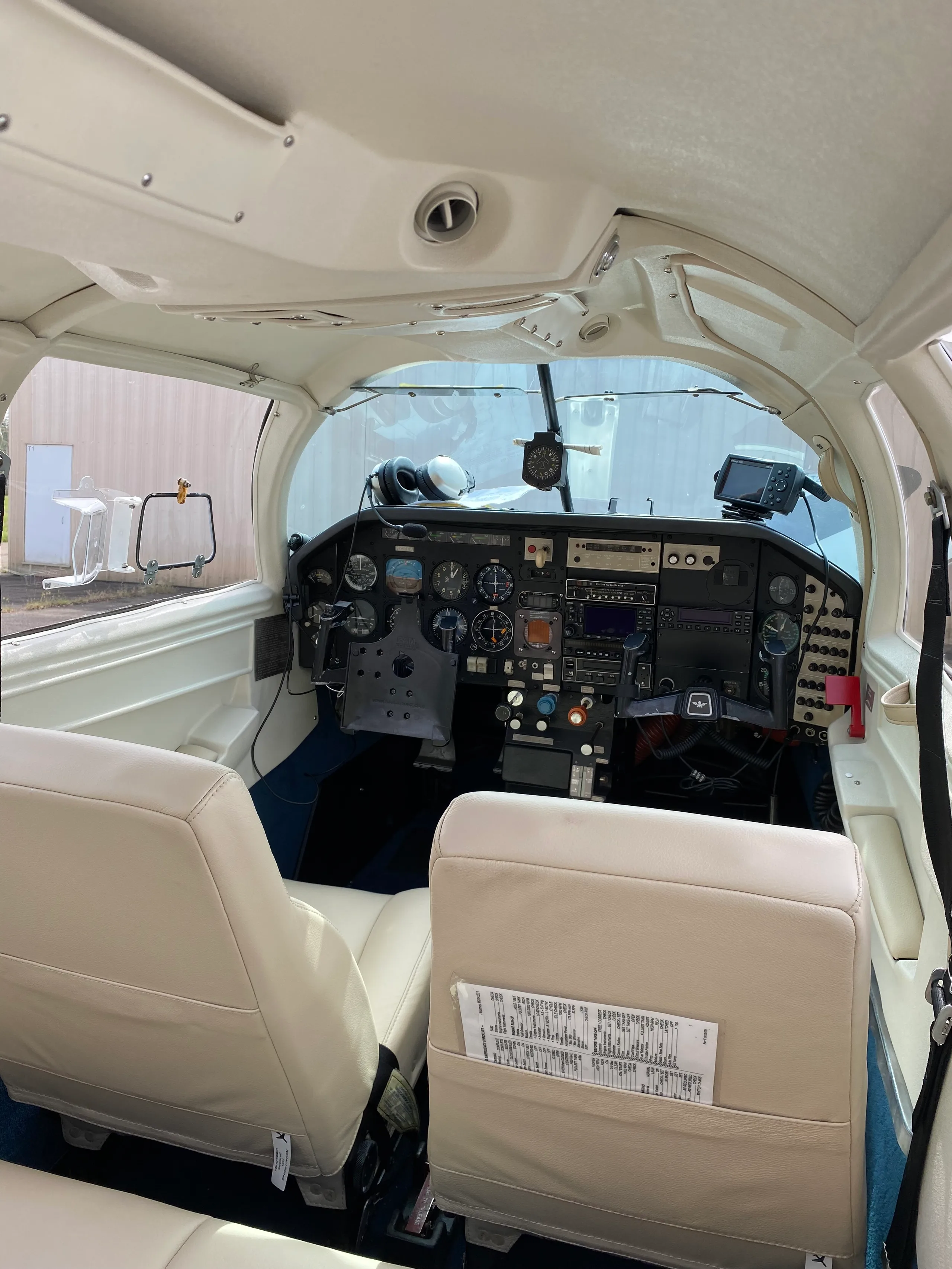 View from the cabin into the cockpit, showing the instrument panel and cream-colored pilot seats.