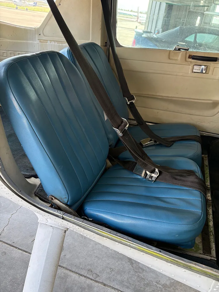 Two blue vinyl passenger seats with seatbelts in the aircraft cabin.