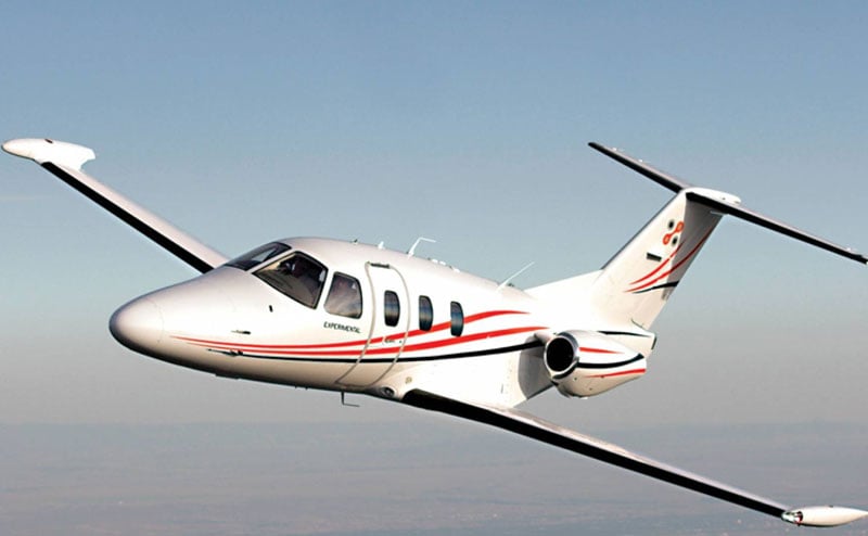 A Cirrus Vision SF50 aircraft in flight with a white and red paint scheme.