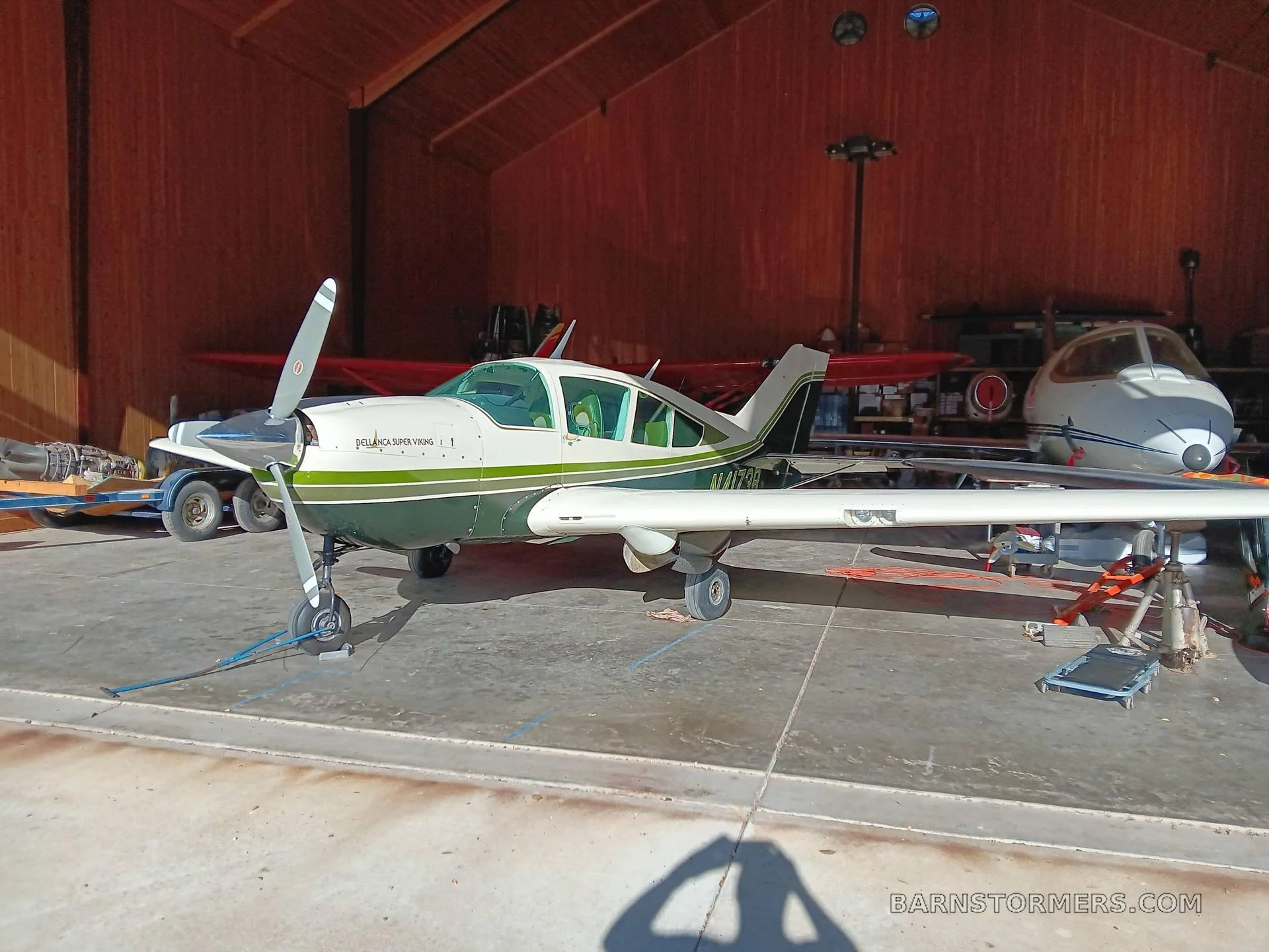 A white and green Belanca Super Viking aircraft parked inside a wooden hangar.
