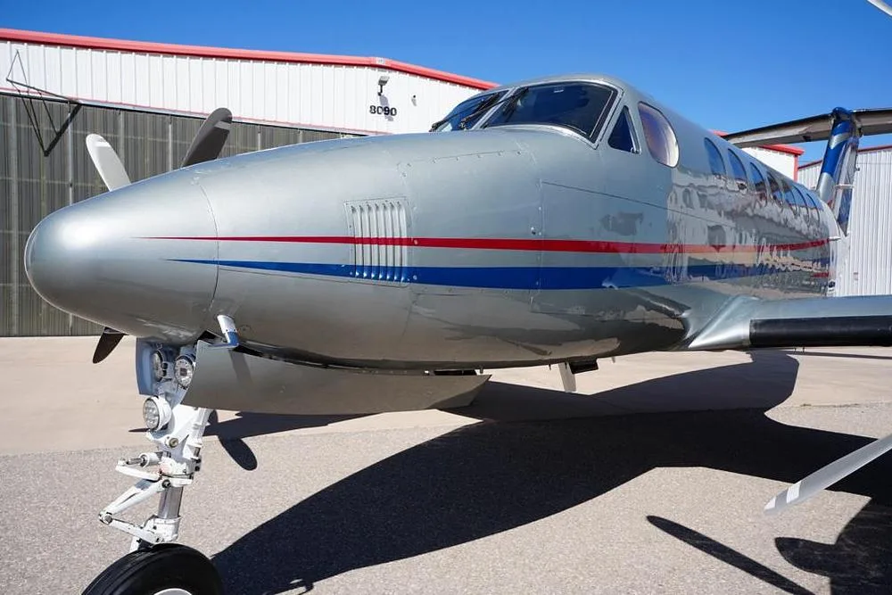 A front-side view of the silver and blue twin-turboprop aircraft N819EE, showing the nose and cockpit area.