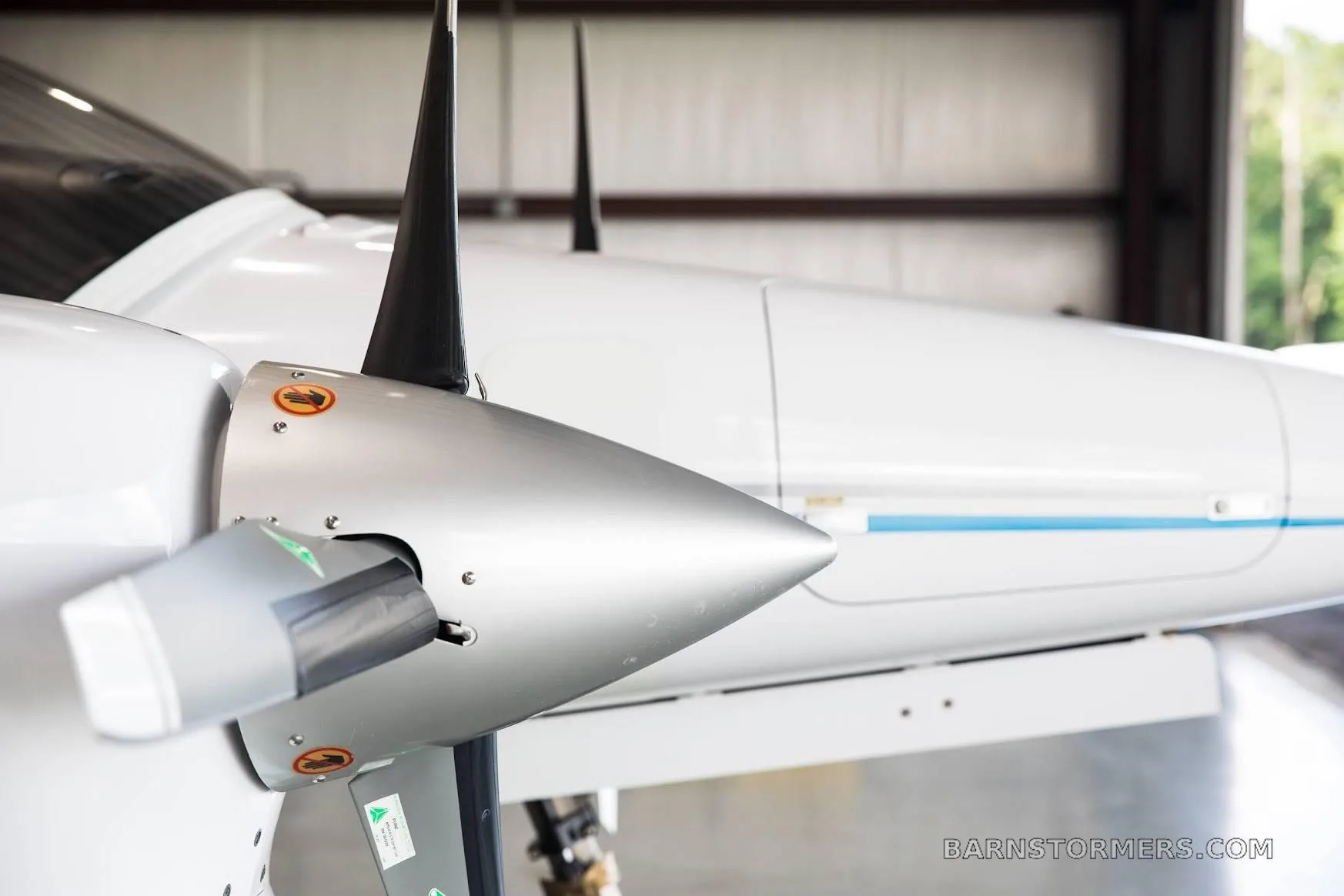Close-up of the silver propeller and white engine cowling of a Diamond DA42 aircraft.