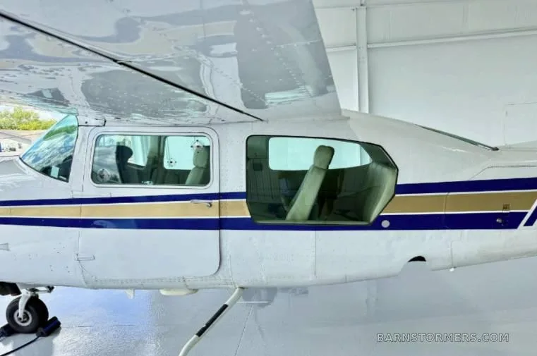 A close-up side view of the white aircraft's fuselage with blue and gold stripes, showing the windows and wing.