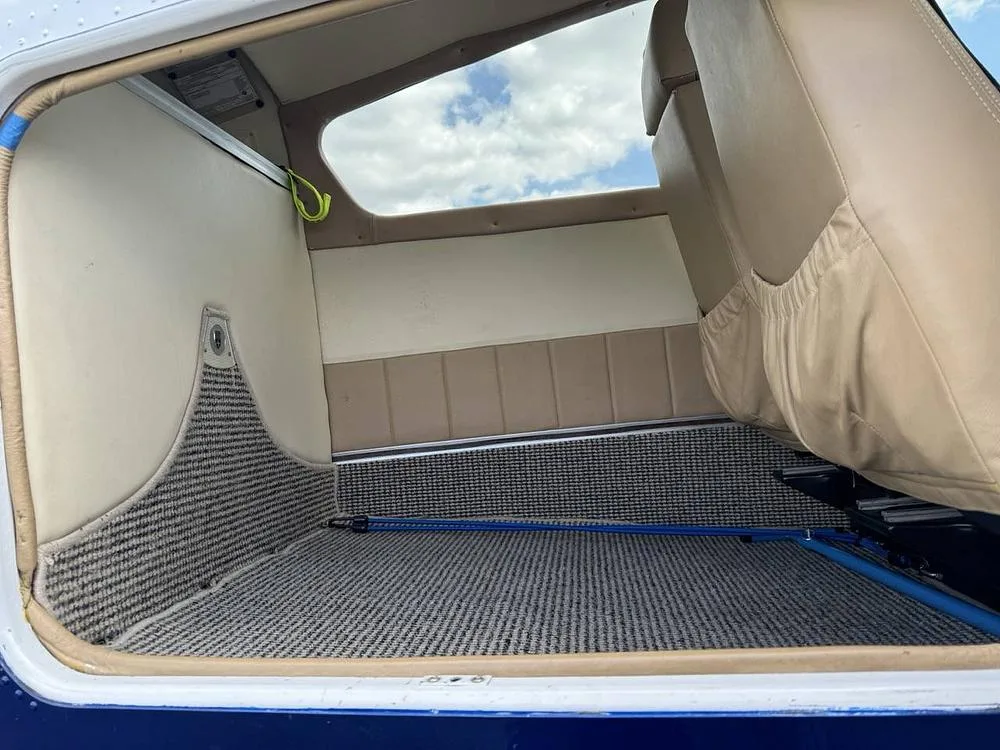The rear cargo area of a small aircraft, featuring patterned carpet and tan side panels.