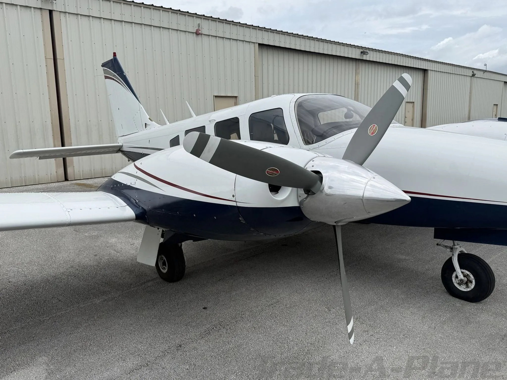 Close-up front-right view of the white and blue twin-engine propeller aircraft, showing the right engine and propeller.