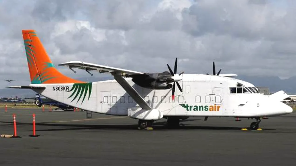 A Transair aircraft on the tarmac with an orange tail.